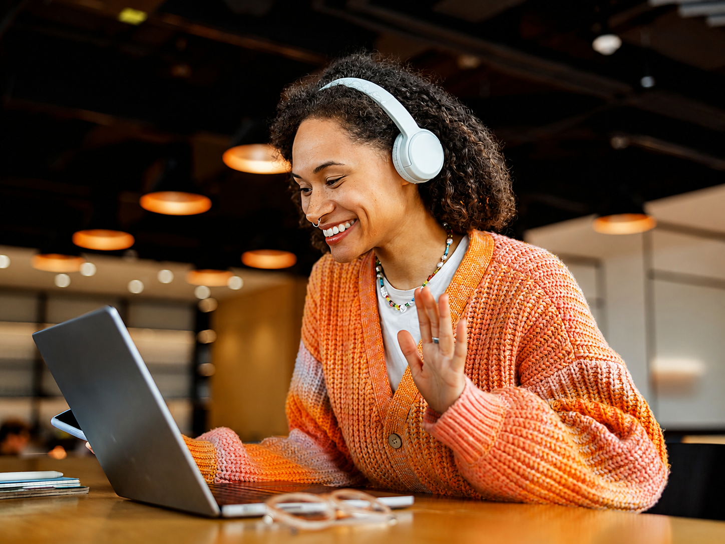 Woman with headphones smiling during a virtual training call on her laptop